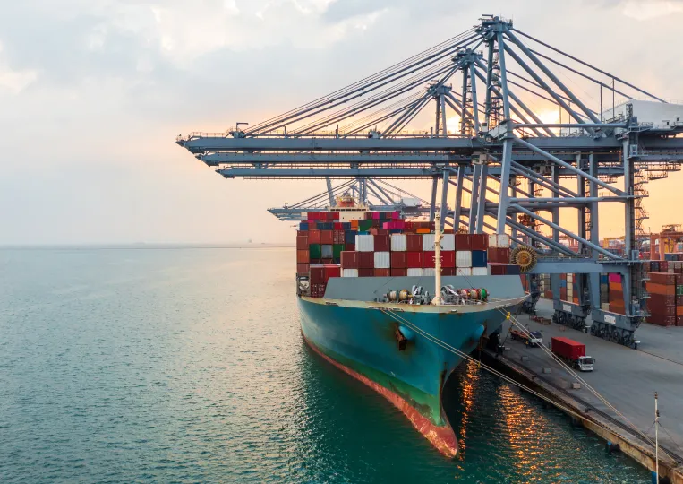 Ocean freight supply chain TOP Worldwide ocean freight with a cargo ship being loaded at a port, illustrating efficient import and export logistics.