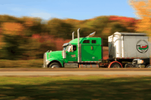 TOP Worldwide semi truck driving on a highway, symbolizing the vital role of trucking in the U.S. economy and its contribution to efficient freight transportation.