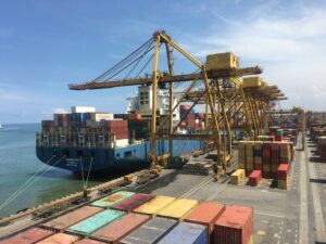 TOP Worldwide drayage services facilitating the efficient loading of shipping containers at a bustling port, ensuring seamless transitions from sea to land transport for global trade.